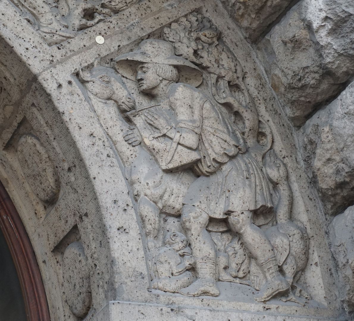 Fassadenschmuck am Melanchthon-Gymnasium "Musik", eine männliche Gestalt umgeben von Tieren, welchem sich ihm zuwenden, trägt eine Lyra