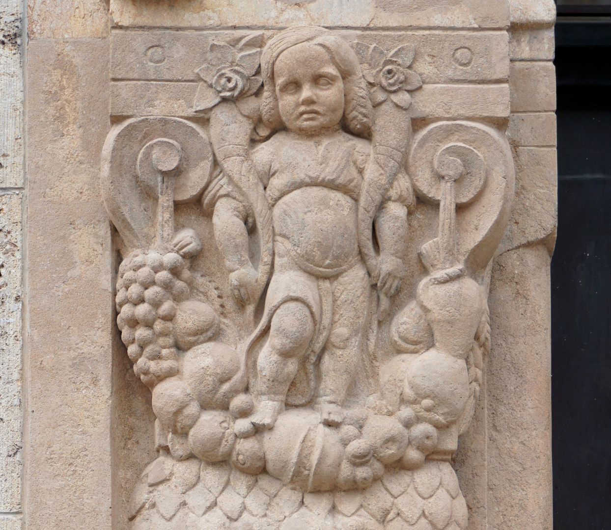 Portal linke Portallaibung, Detail mit Kind, welches auf einem Fruchtgehänge steht und zwei Füllhörner trägt (Hinweis auf Abundantia?)