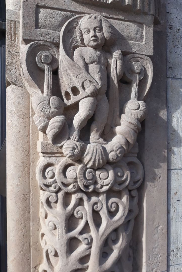 Portal rechte Portallaibung, Detail mit Putto auf einem Muschelgehänge stehend und einem vom Wind aufgeblähtem Segeltuch über den Schultern / Schrägansicht