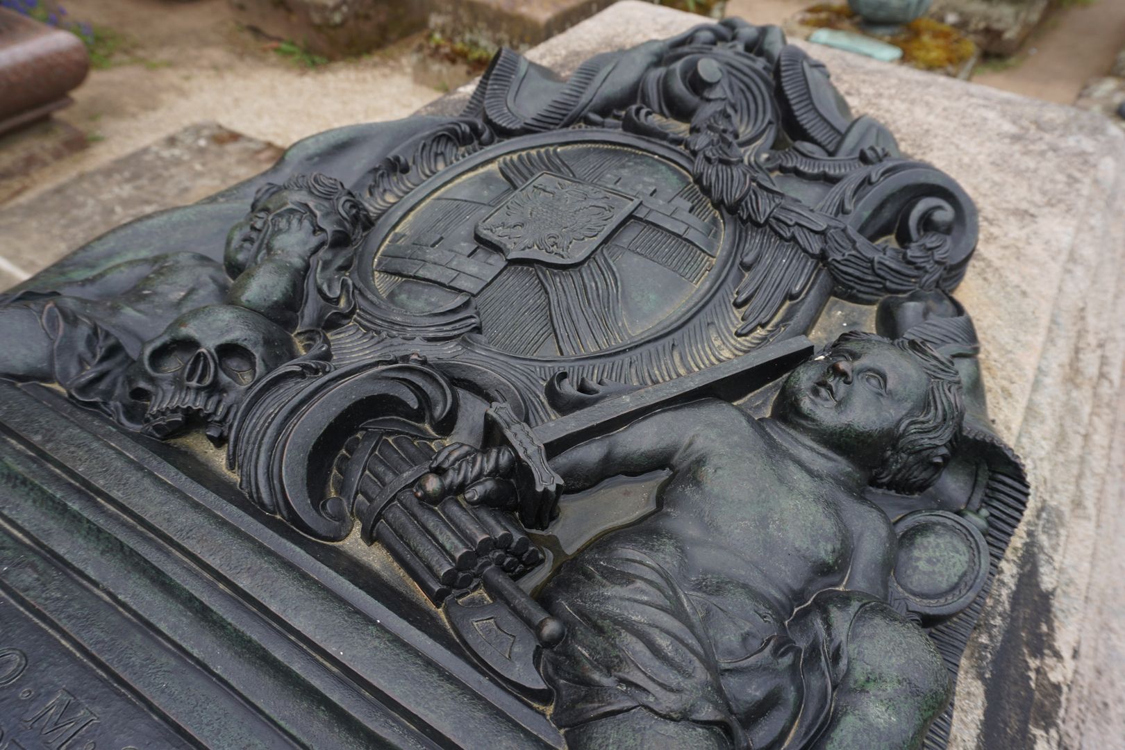 Grabstätte des Carl Friedrich Behaim Putti unterhalb des Wappens mit Totenschädel, Rutenbündel mit Beil (Fascis), Schwert und Spiegel