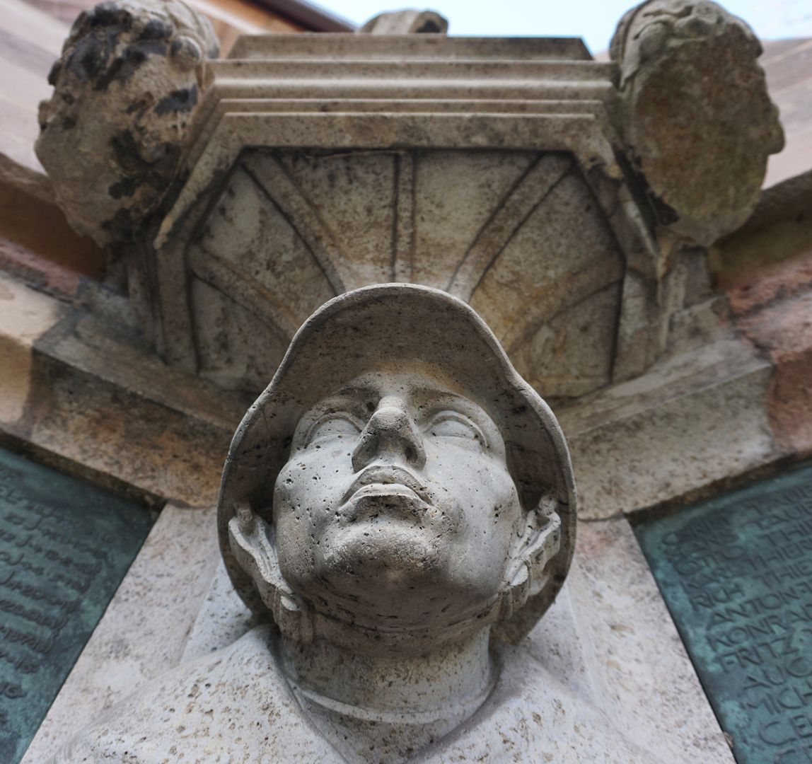 Kriegerdenkmal Soldat mit Stahlhelm aus dem sich die Konsole für die darüberliegende Kreuzigungsgruppe bildet