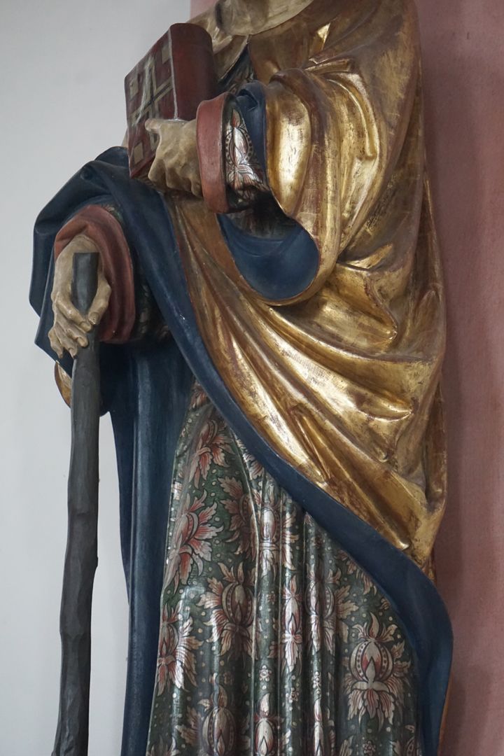 Apostel Judas Thaddäus Mit seiner rechten Hand hält er sein Marterinstrument, eine Keule. Mit seiner linken Hand hält er ein Buch.