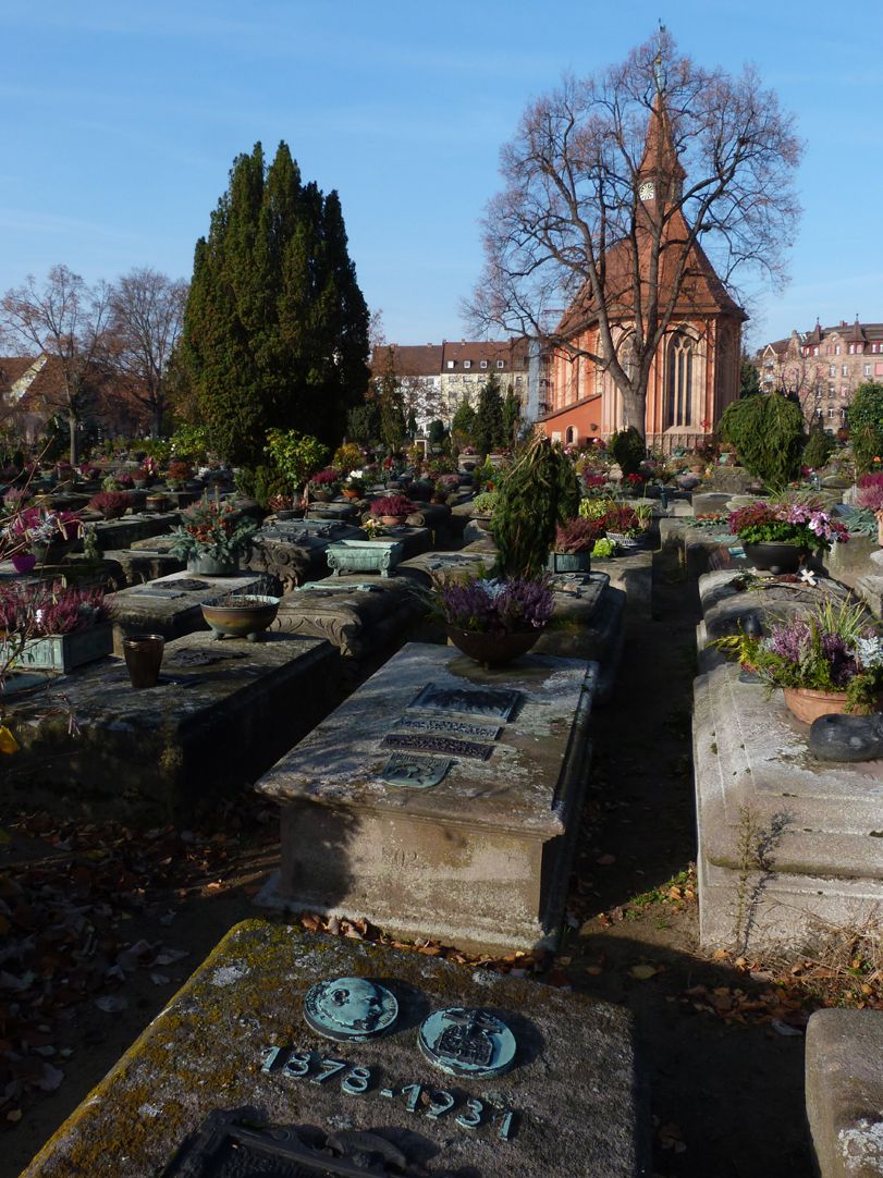 Epitaph Rudolf Schiestl Grab 836, Johanniskirche im Hintergrund