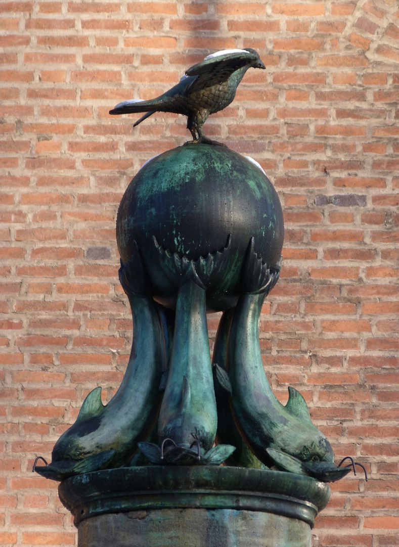 Symbolbrunnen Brunnenfigur von Süd: Ein Vogel sitzt auf einer von Delphinen getragenen Kugel